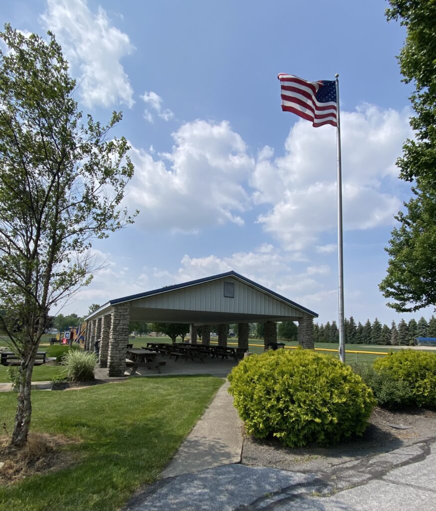 Danbury Township shelter house with flag pole in foreground with American flag blowing